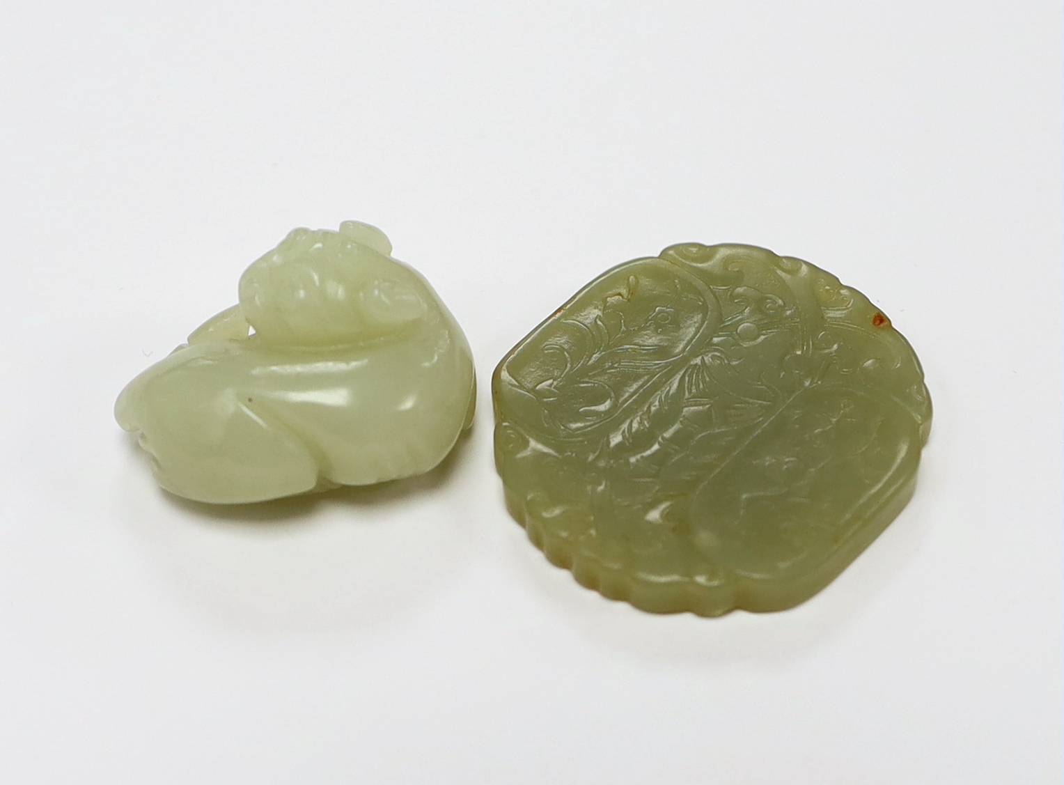 A Chinese carved jade pendant and another carving of a recumbent lion dog, largest 5cm